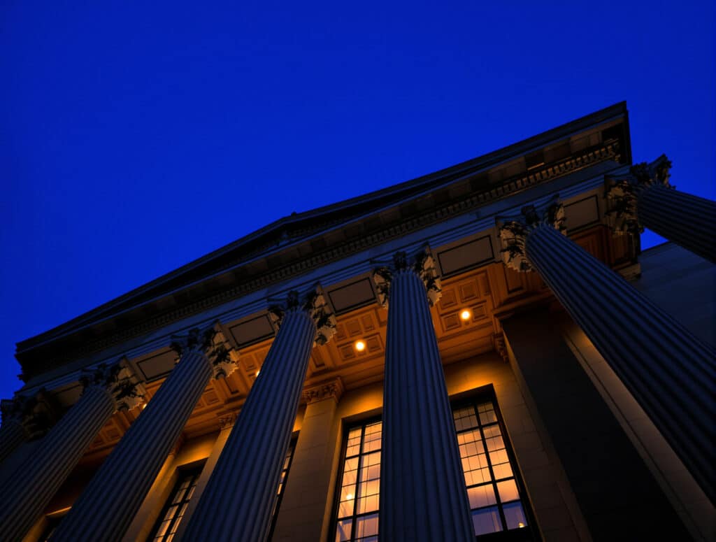 Neoclassical government building columns lit at dusk, representing the IGJ company registry in Argentina
